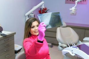 une femme assise sur une chaise de dentiste tenant un miroir